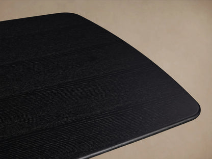 Saint Germain dining table with solid oak wood top and oak veneer base, finished in dark Ebony, set on wooden floor.
