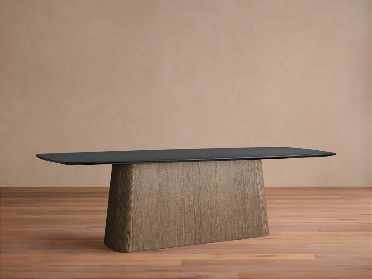 Saint Germain wood dining table featuring a solid ebony-finished oak top and a trapezoidal plywood base on a wooden floor.