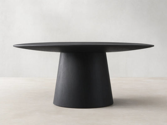 Round dining table with dark wood finish. Flat top supported by a conical base on wood floor against beige wall.