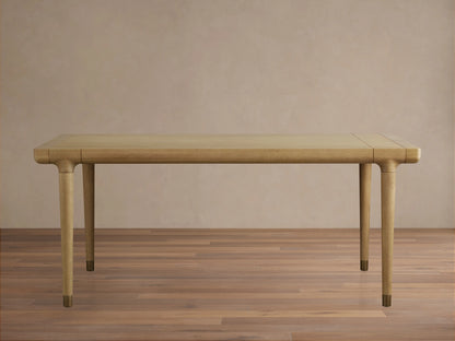 Eletta Dining Table, light oak, rectangular with rounded corners. Tapered legs with brass-colored caps, set on a wood floor.