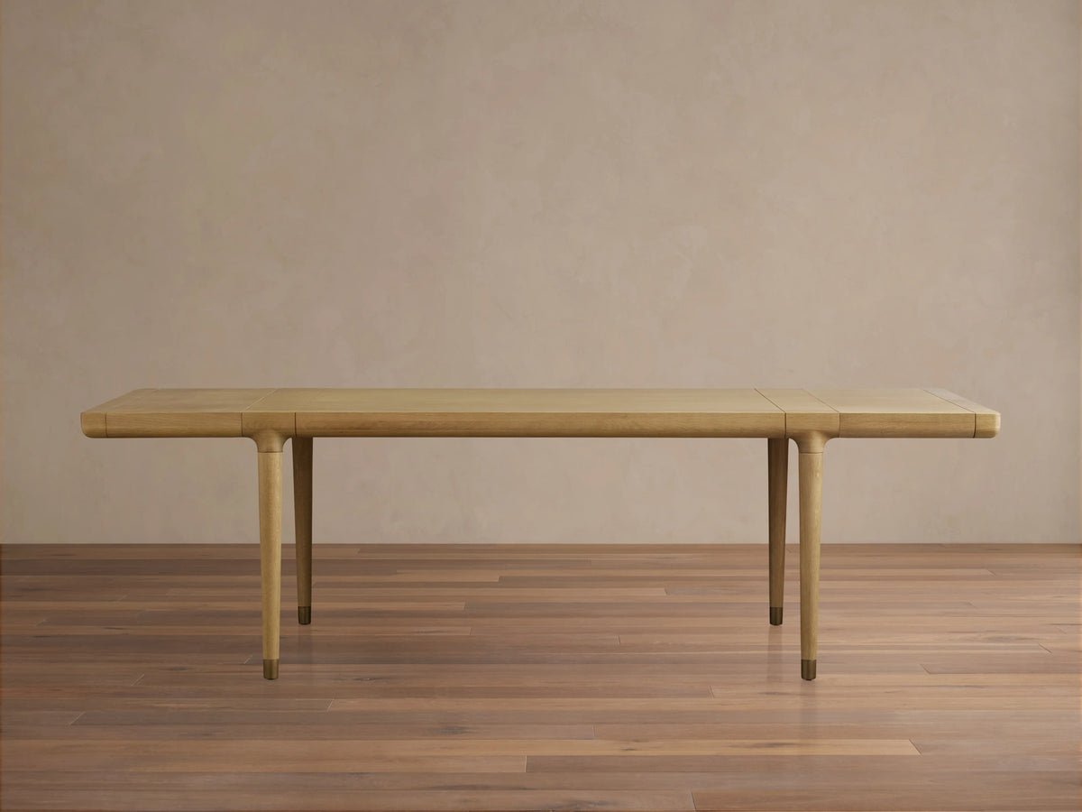 Rectangular Eletta Dining Table crafted from light oak wood, featuring a lacquered finish, tapered legs, and metal feet.