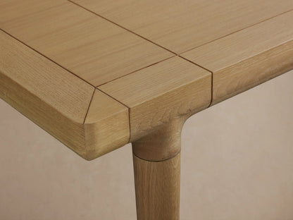 Eletta Dining Table: Light European white oak with lacquered finish, rectangular top showing extensions, tapered legs with metal caps.