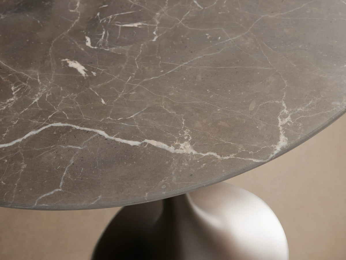Saint Germain Bistro Table with round black marble top and sleek brown steel base on wooden floor.