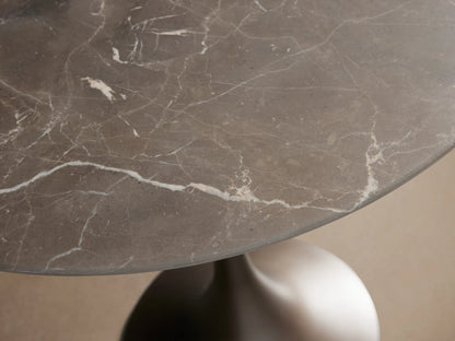 Saint Germain Bistro Table with round black marble top and sleek brown steel base on wooden floor.