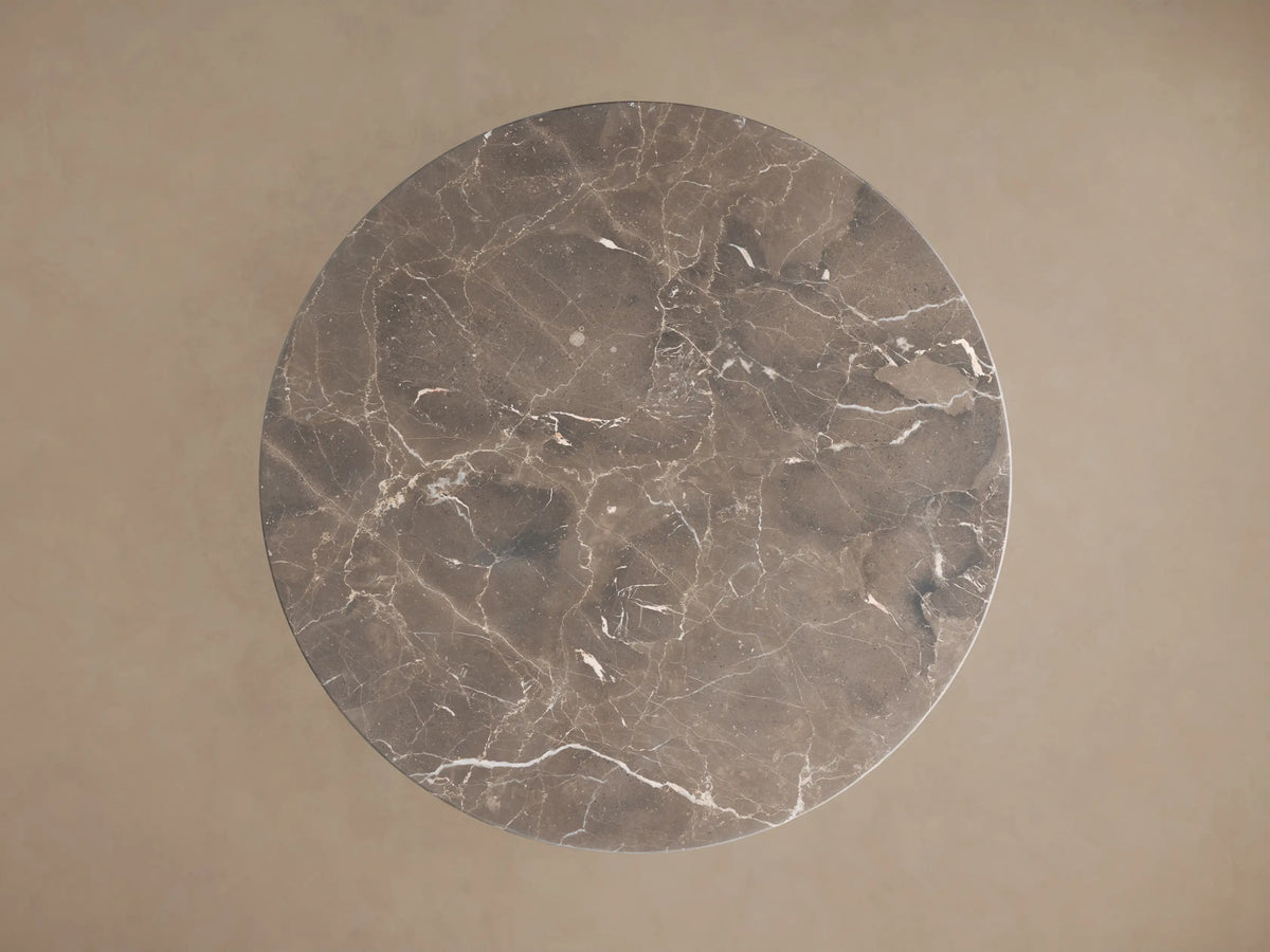 Saint Germain Bistro Table with a round black marble top and a gold steel pedestal base, on a wooden floor.