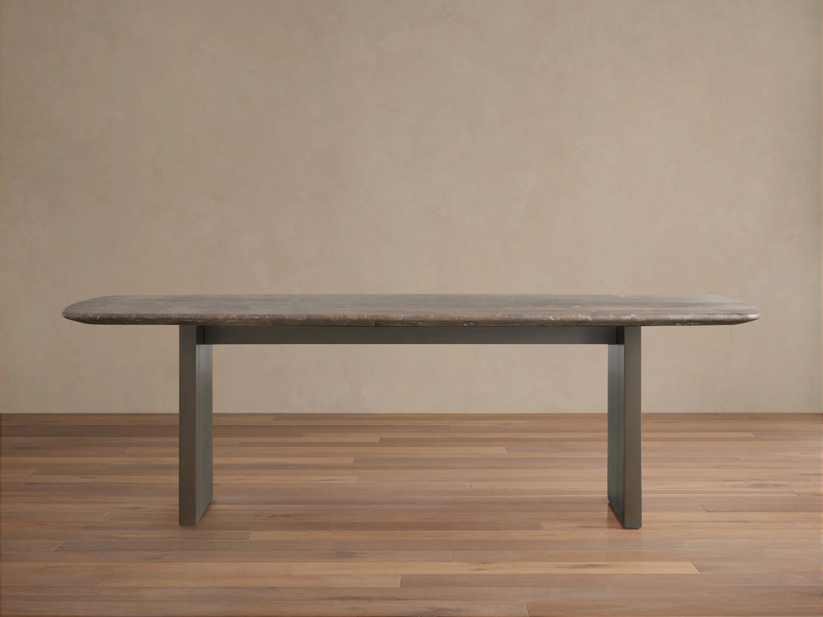 Saint Germain Stone Dining Table with oval espresso brown stone top and rectangular wood base on a wooden floor.
