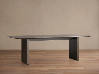 Saint Germain Stone Dining Table with a flat stone tabletop and a Clement Base in dark finish, placed on a wooden floor against a plain wall.