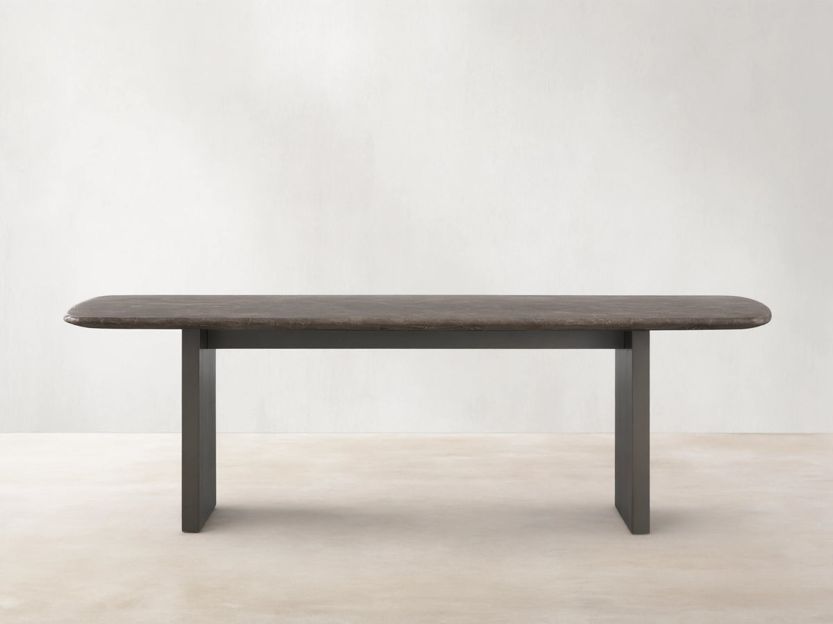 Saint Germain Stone Dining Table with oval espresso brown stone top and rectangular wood base on a wooden floor.