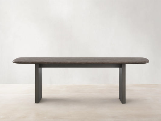 Saint Germain Stone Dining Table with oval espresso brown stone top and rectangular wood base on a wooden floor.