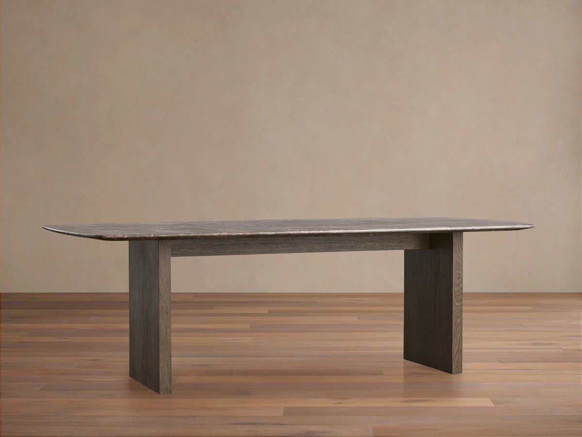 The image shows a close-up of the Saint Germain Dining Table with an espresso brown stone top, featuring natural veining and unique texture.
