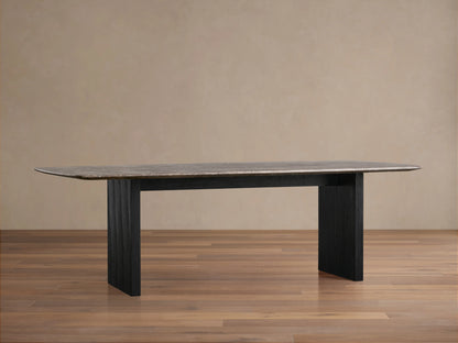 Saint Germain dining table with a dark stone top and a black wooden base on a wooden floor, against a beige wall.