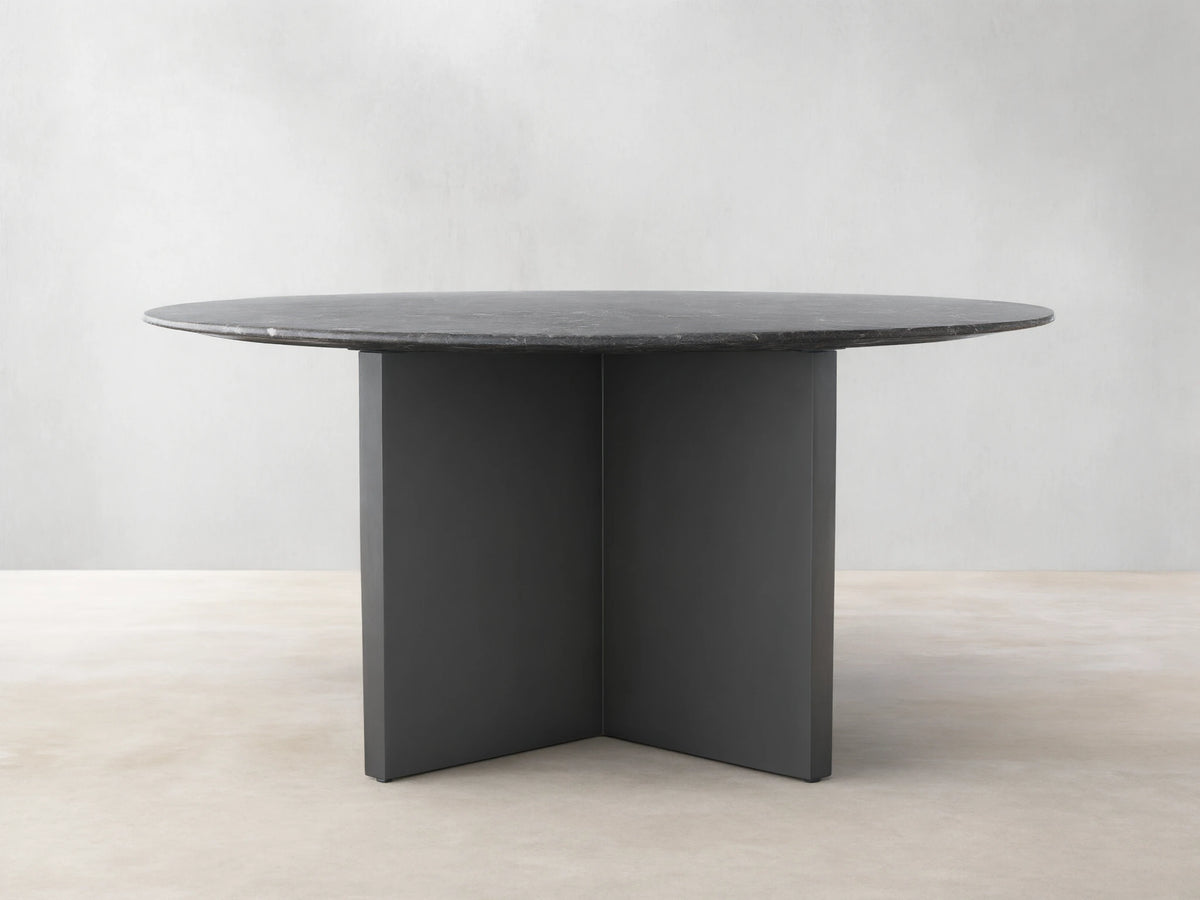 Saint Germain Round Stone Dining Table with a dark stone top and two-tone Clement base on a wooden floor.