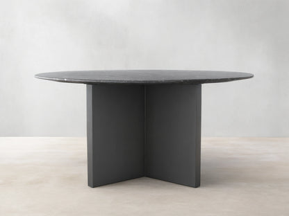 Saint Germain Round Stone Dining Table with a dark stone top and two-tone Clement base on a wooden floor.
