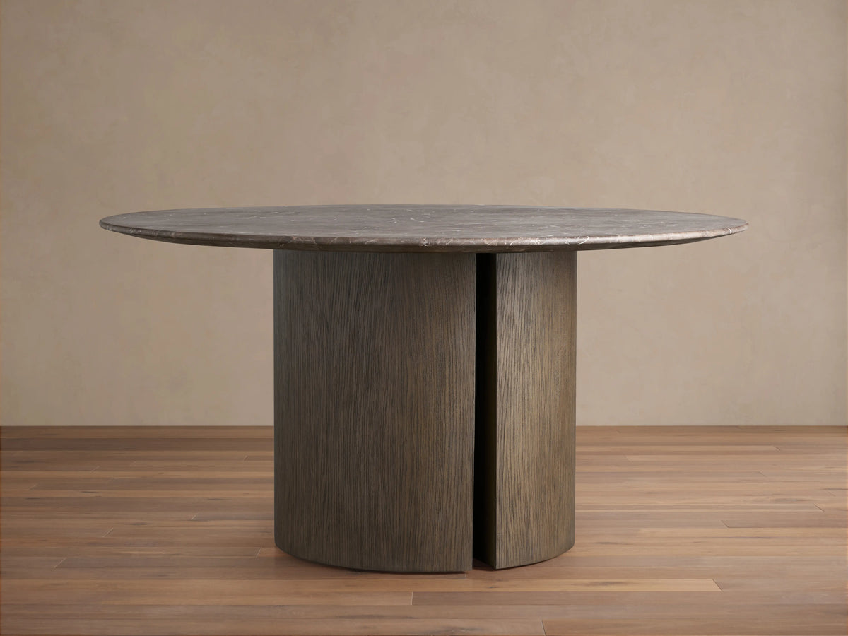 Round stone dining table with a sleek, dark espresso brown top, featuring unique natural patterns, supported by two curved, wood-grain textured bases on a wooden floor.