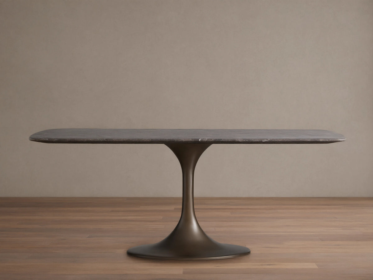 Saint Germain Stone Dining Table features a rectangular stone tabletop with veining on a sturdy, dark steel Launette base, on wooden floor.