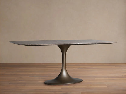 Saint Germain Stone Dining Table with a rectangular marble top and a sleek, bronze-toned Launette steel base, on a wooden floor.