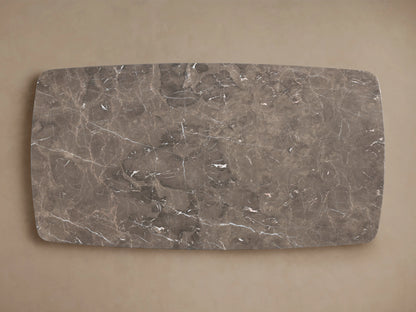 Dining table with a rectangular stone top, possibly espresso brown stone, on a dark wood base. Set on wooden flooring against a neutral wall.