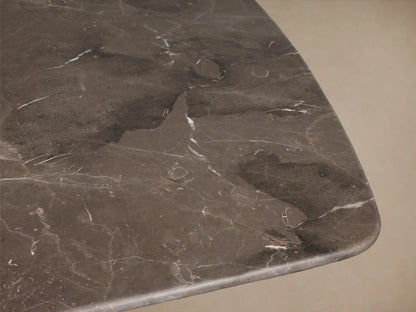 Stone dining table with rectangular marble tabletop in dark hue, supported by two cylindrical wooden bases on wood floor.