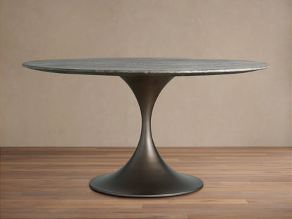 Saint Germain Round Dining Table with a dark metal base and a smooth, circular stone tabletop, set on wooden flooring.