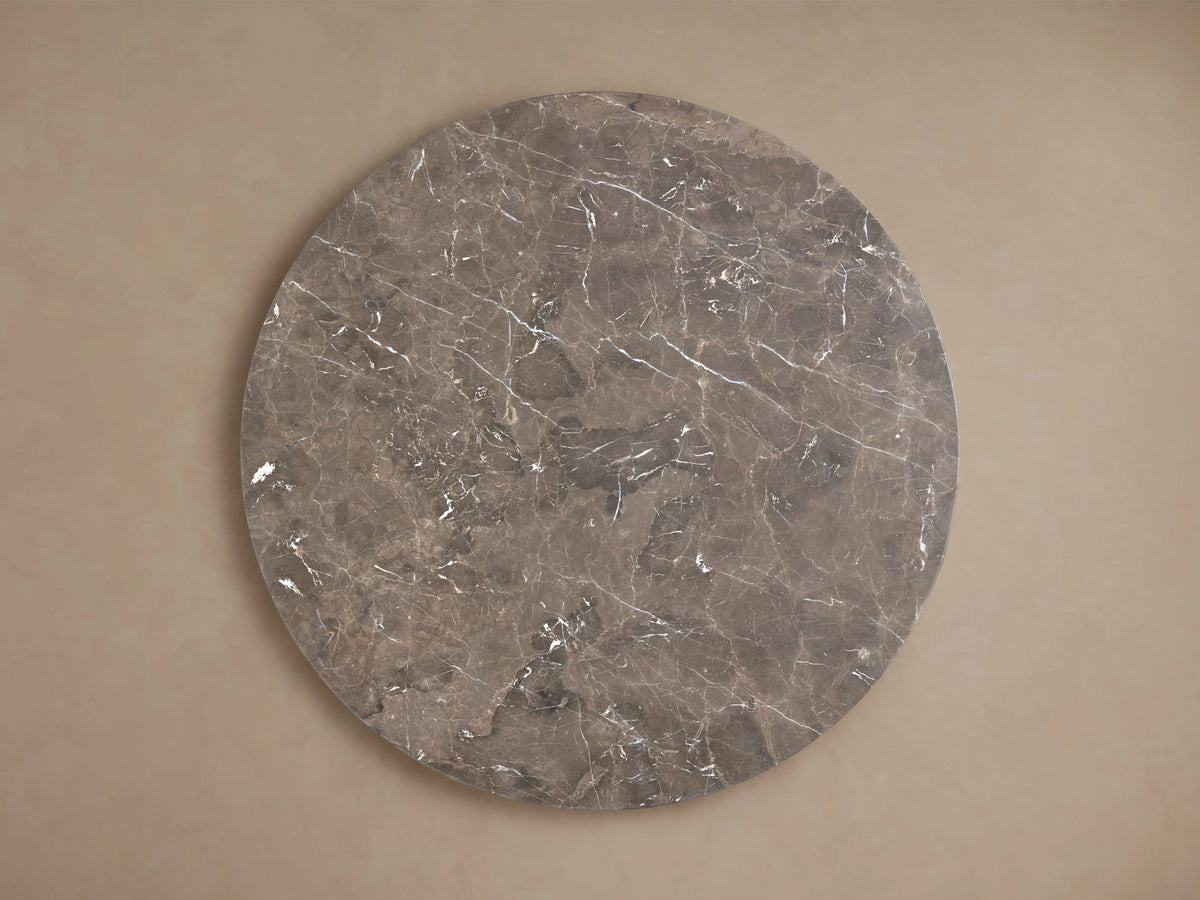 Round Carrara marble tabletop with unique gray veining and swirling patterns, set against a neutral background.