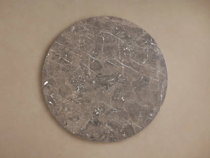 Round Carrara marble tabletop with unique gray veining and swirling patterns, set against a neutral background.