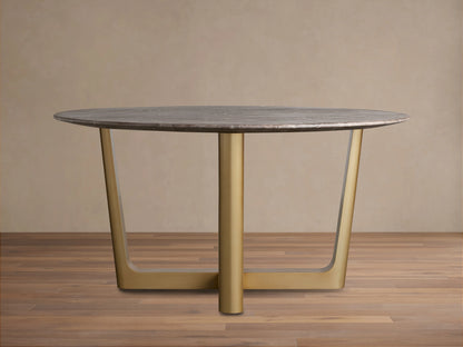 Saint Germain Round Stone Dining Table with gray stone top and gold Rennes steel base, shown on wooden floor, neutral wall background.