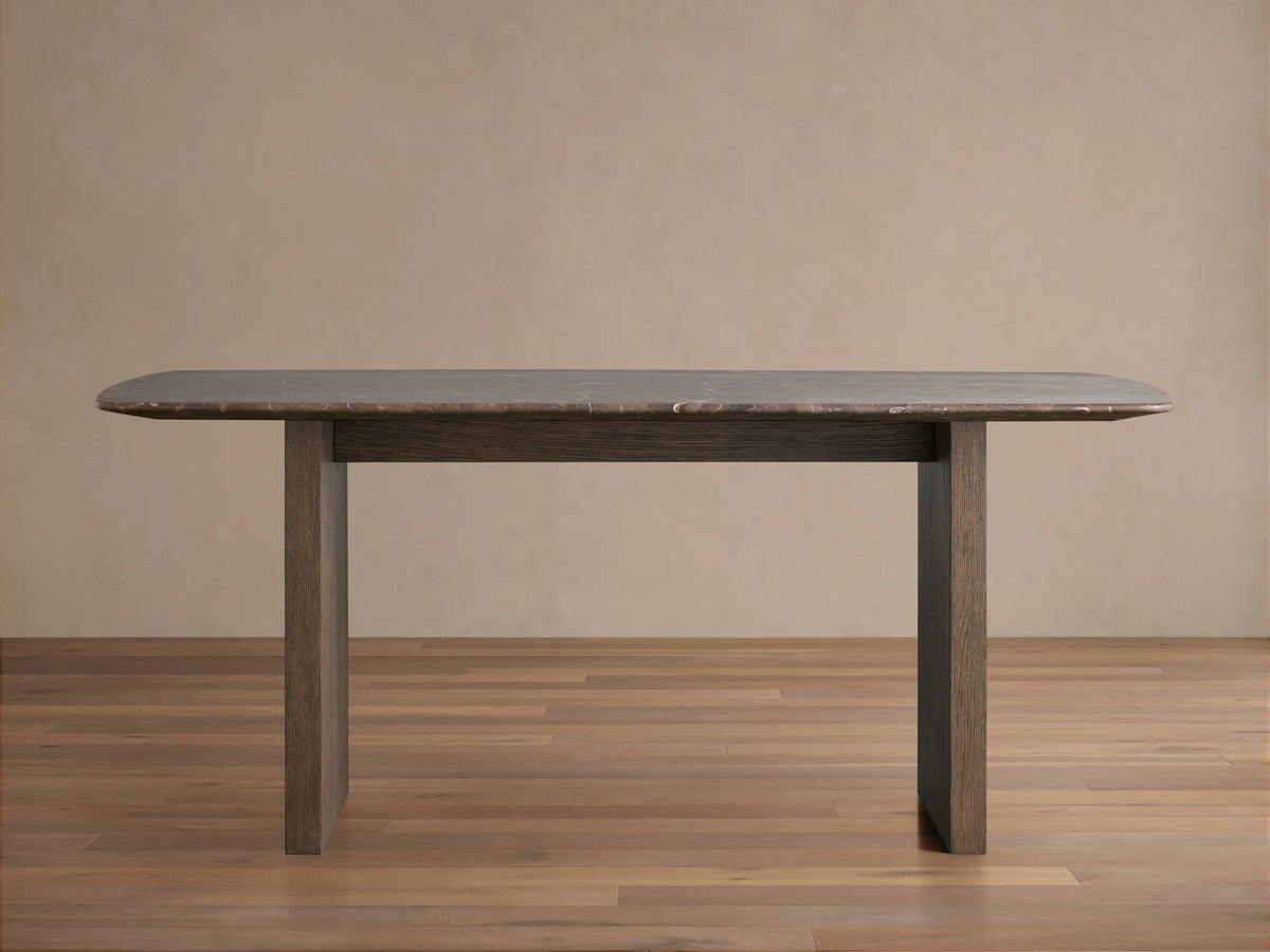 Saint Germain dining table with a rectangular stone top and a wood base in a neutral room. The table is positioned on a wooden floor.