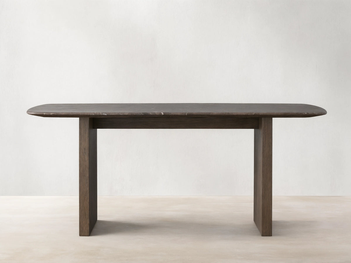 Saint Germain dining table with a rectangular stone top and a wood base in a neutral room. The table is positioned on a wooden floor.