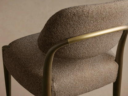 Close-up of the Evelyn Dining Side Chair, showing its textured taupe upholstery, dark mahogany wood frame, and warm brushed brass accent.
