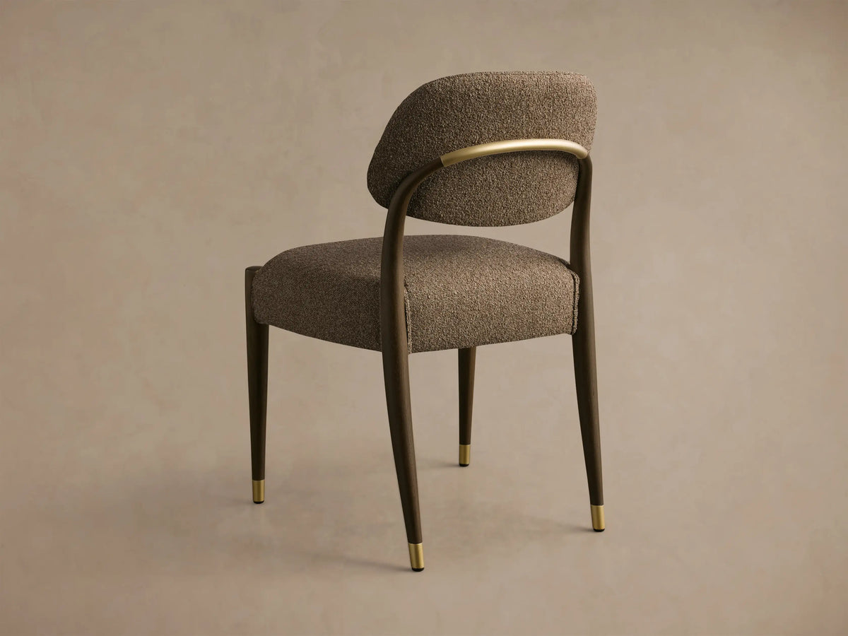 Rear view of the Evelyn Dining Side Chair with textured brown upholstery, dark wood frame, a curved brass back accent, and brass leg caps.