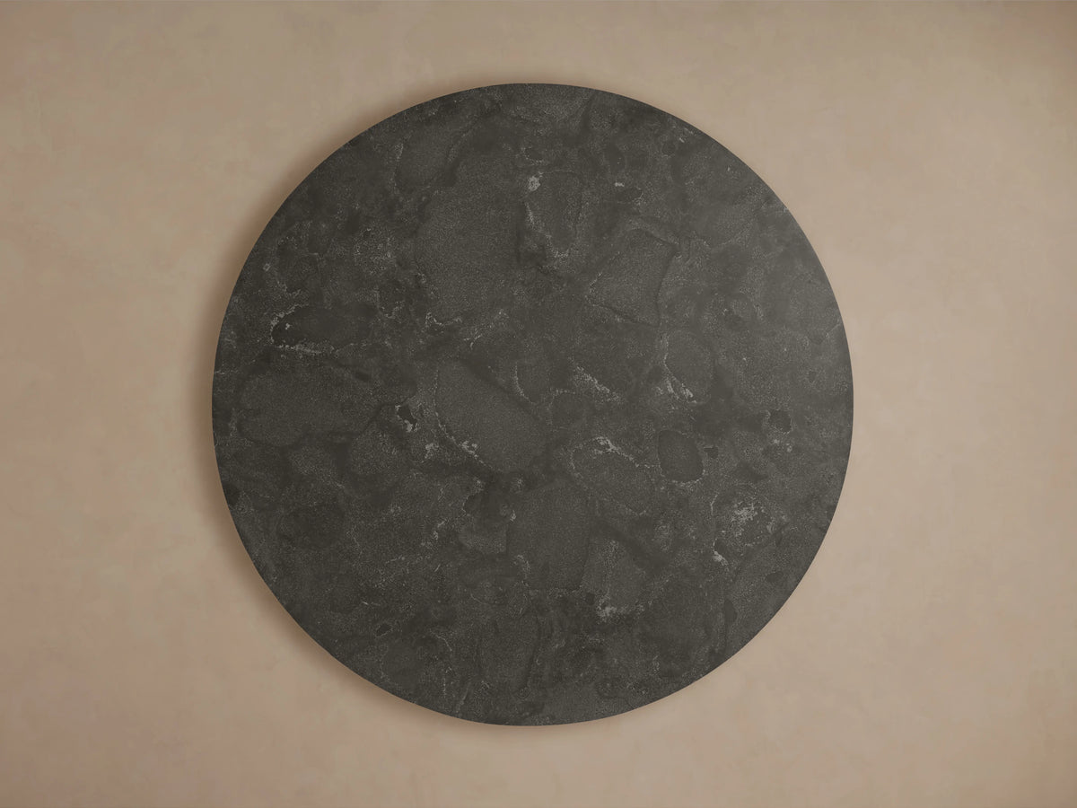 Finnley Round Dining Table with dark bluestone top, smooth surface, and subtle texture, resting on light brass plinth base.