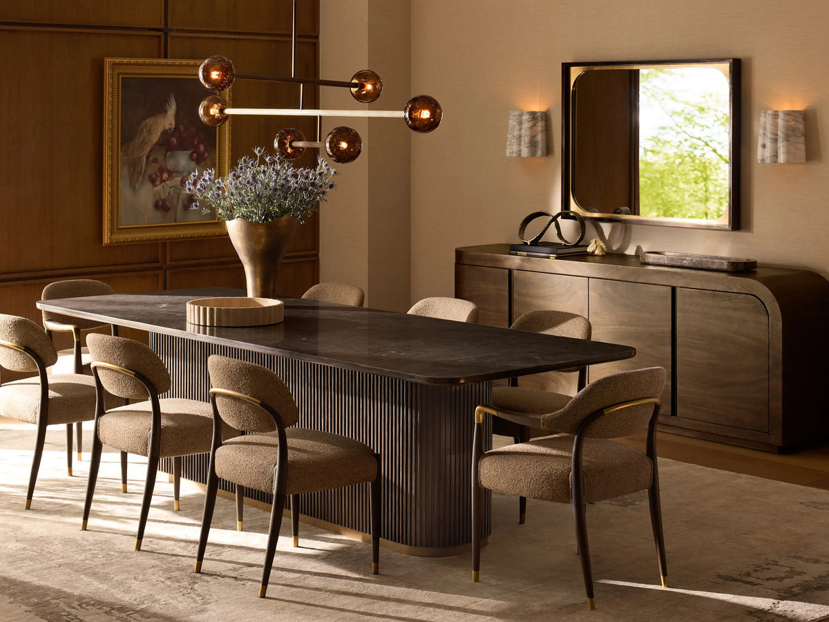 Finnley Dining Table with a white rectangular marble top, dark vertical ribbed base, and light brass plinth on wooden floor.