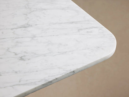 Finnley Dining Table showing a close-up of the white Carrara marble top with gray veining, smooth edges on a neutral background.