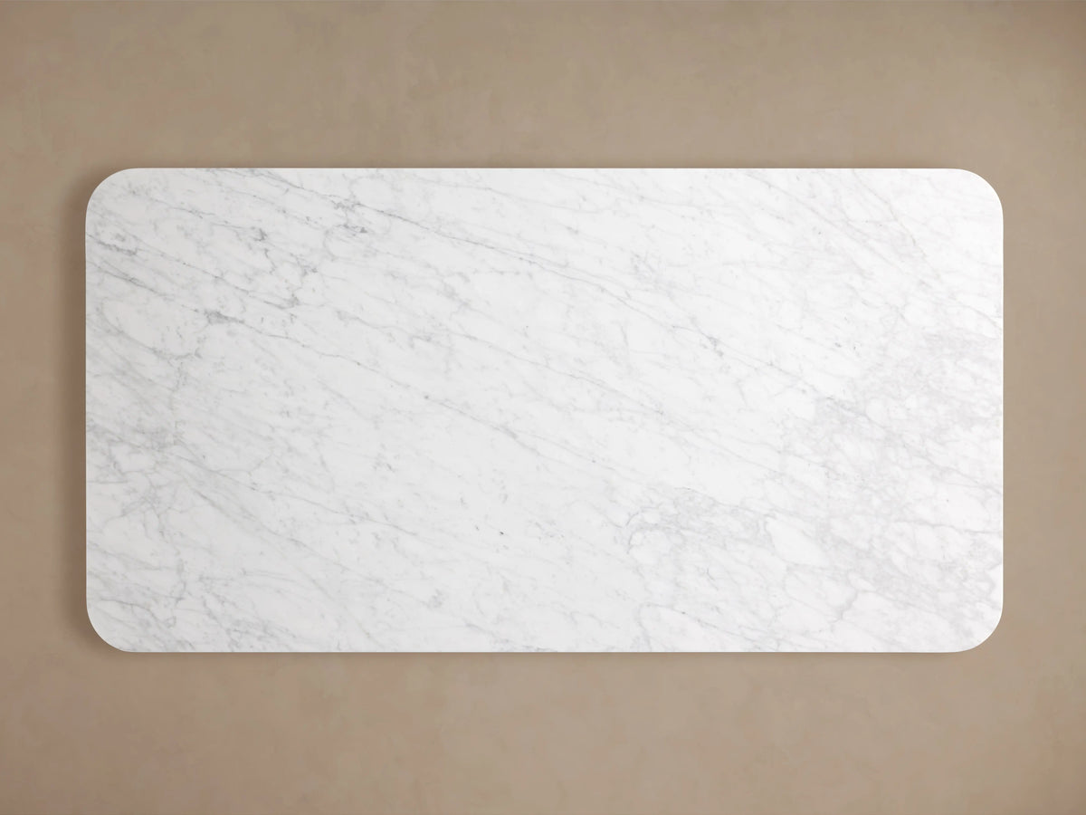 Finnley Dining Table with a rectangular Carrara marble top, white with gray veining, against a neutral background.