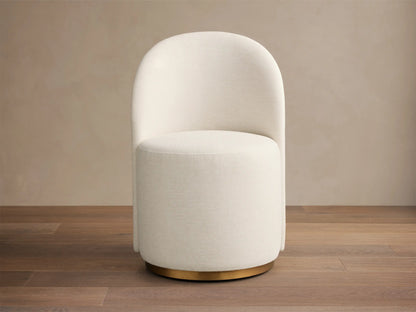 Front-right view of Finnley Dining Side Chair with off-white upholstery, Ebony reeded wood back, and brass plinth base.