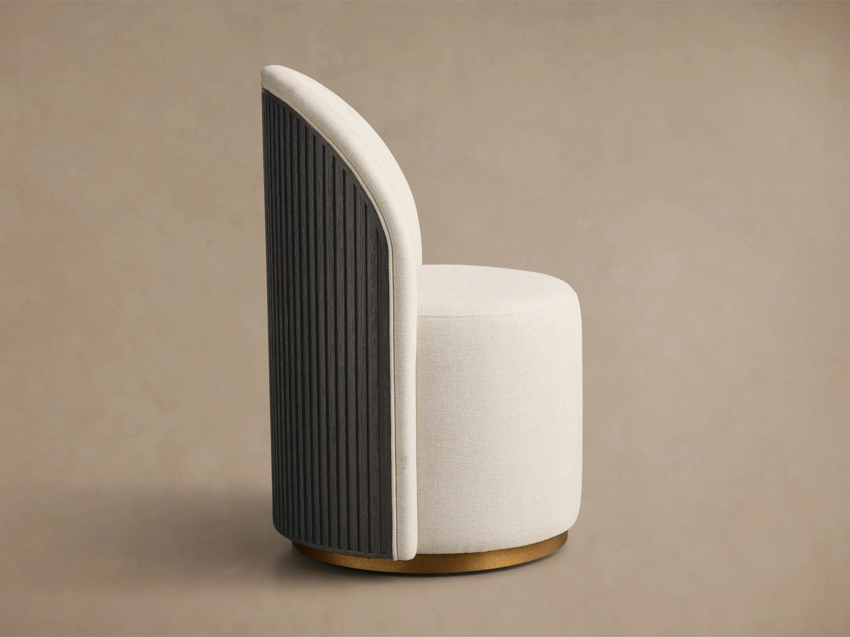 Front view of a cream Finnley Dining Side Chair, featuring a rounded back, cylindrical seat, and a light-finished brass plinth base.