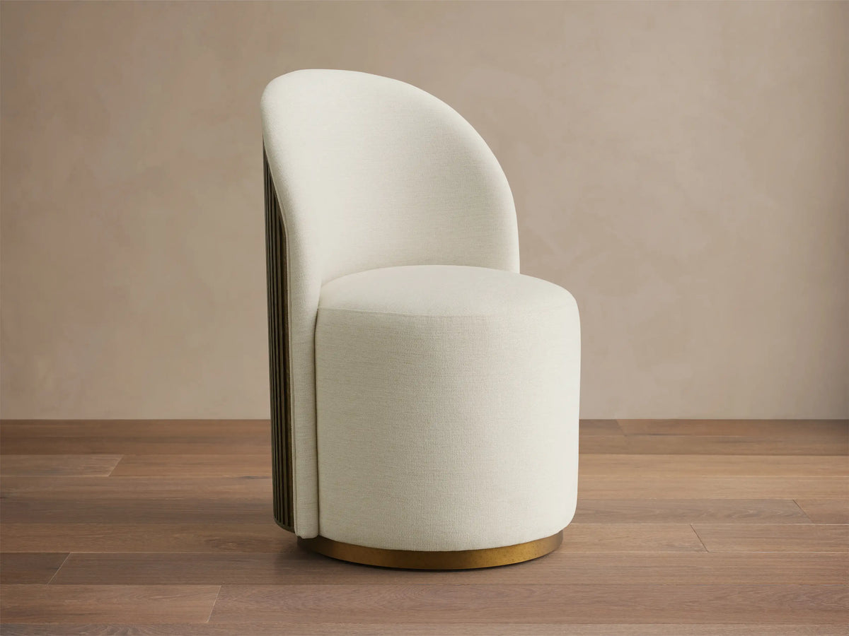 Cream Finnley Dining Side Chair, front-facing, with a curved back, dark reeded wood paneling, and a brass plinth base.