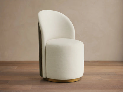 Cream Finnley Dining Side Chair, front-facing, with a curved back, dark reeded wood paneling, and a brass plinth base.