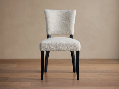 Fallyn Dining Side Chair with white textured upholstery and dark wood legs, set on a wooden floor with a beige background.