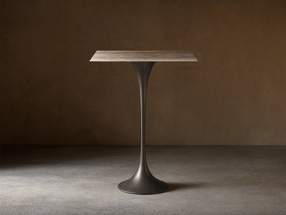 Front view of the Saint Germain Square Bar Table with a light woodgrain square top and a dark tapered pedestal base.