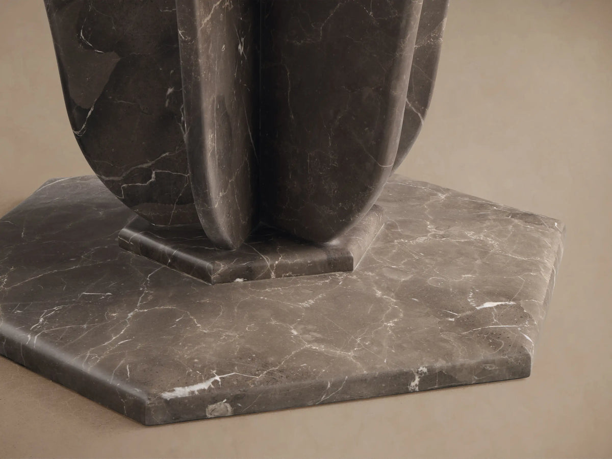 Close-up of the dark gray marble hexagonal base and rounded fin-style supports of the Gabriella Round Stone Dining Table.