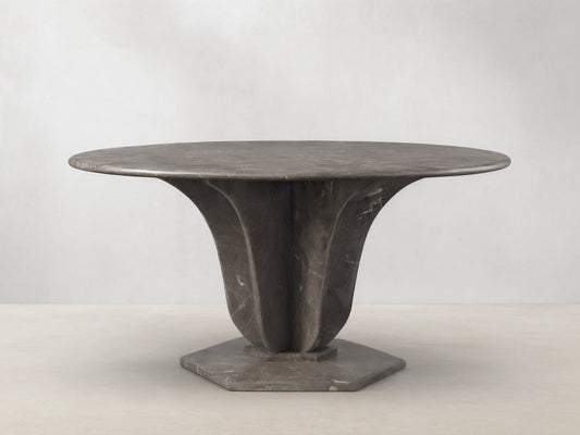 Front view of the Dark grey marble Gabriella Round Stone Dining Table with sculptural fin-style supports and hexagonal base.