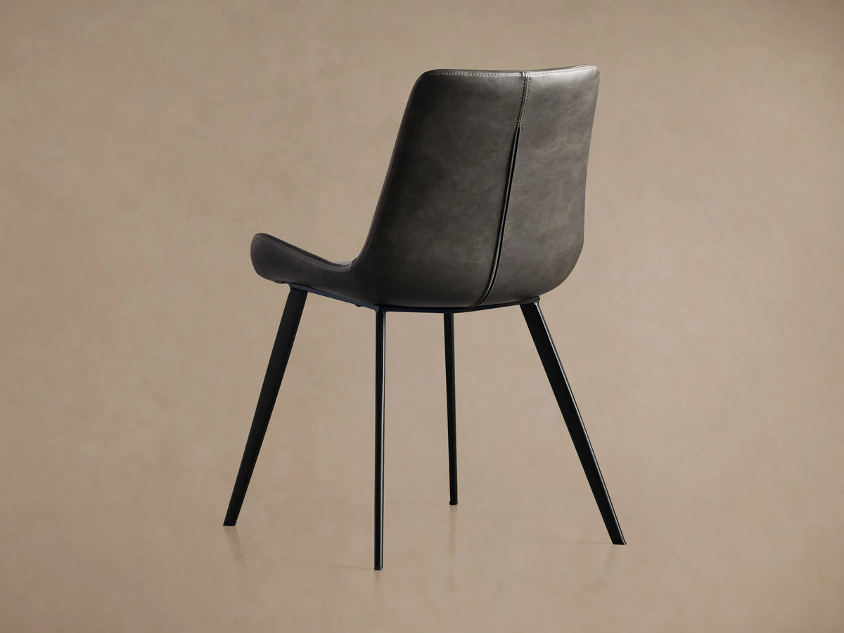 Close-up of Gage Faux Leather Dining Chair's dark gray seat and backrest with prominent baseball-style stitching on seams.