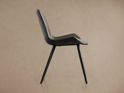 Gage Faux Leather Dining Chair, dark gray, viewed from back-right, showing curved back with stitching & black iron legs.