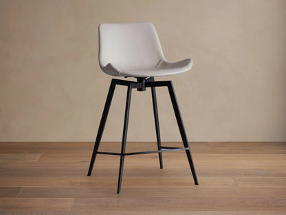 Gage Faux Leather Swivel Stool; light gray faux leather seat with baseball stitching, black iron base, on wood floor.