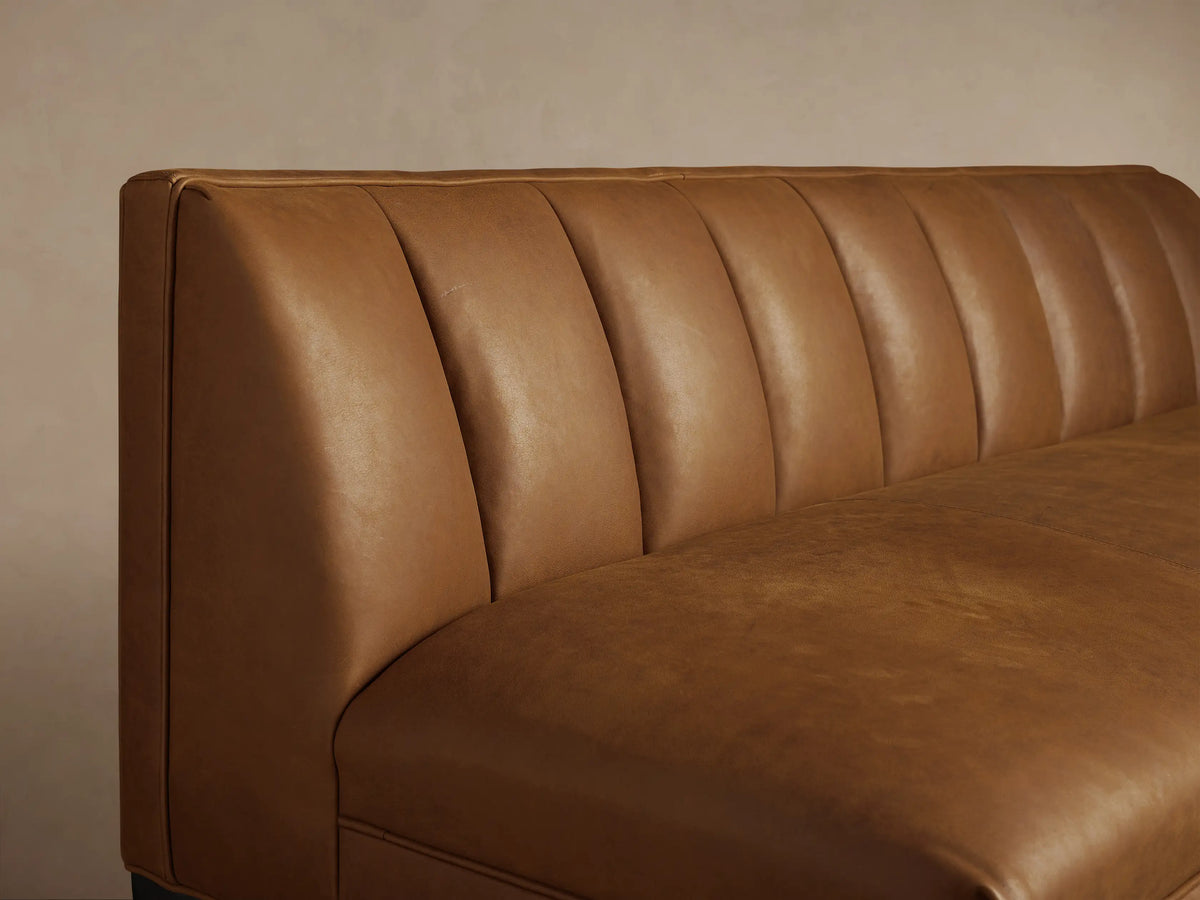 Gates Leather Banquette, L-shaped, in rich brown leather with vertical channel tufting and black tapered legs.