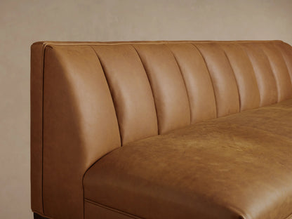 Gates Leather Settee: Distressed light brown leather settee with vertical channeled back, dark tapered legs, on wood floor.