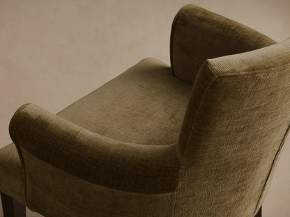 Close-up, angled view of the olive green ribbed Giovanni Dining Arm Chair, showing the padded back and curved armrest.