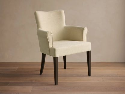 Front view of the cream upholstered Giovanni Dining Arm Chair with dark brown tapered wood legs.