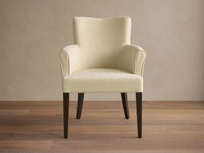 Front view of the cream textured Giovanni Dining Arm Chair with a gently curved backrest, armrests, and dark wood legs.